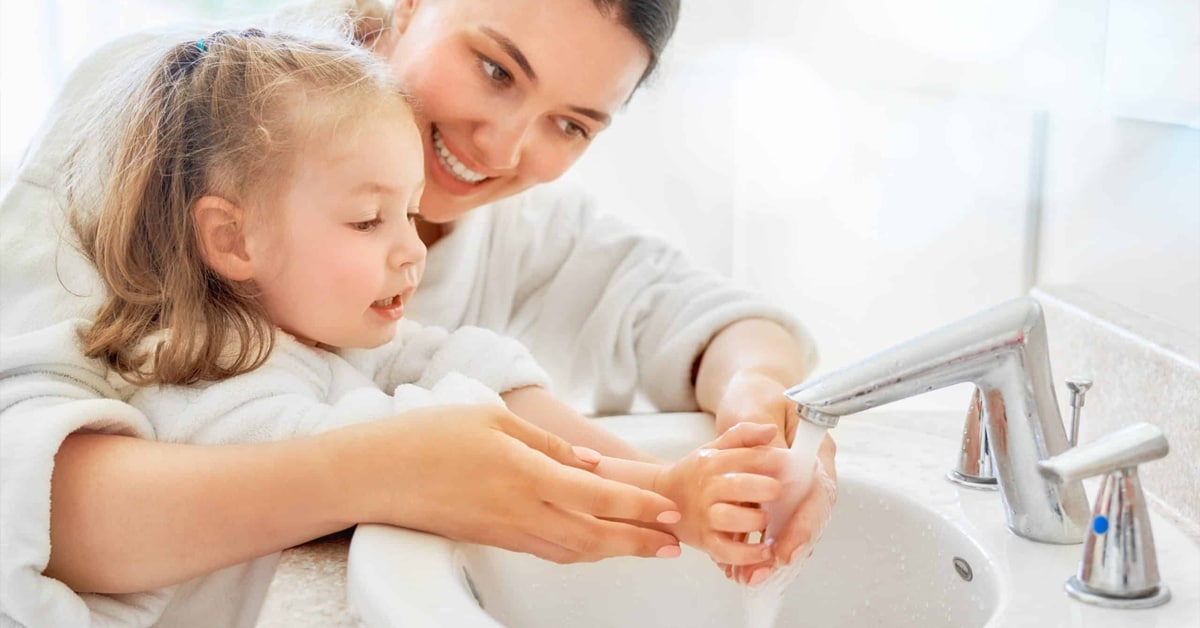 Mom showing daughter how to properly wash hands