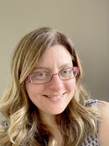 a woman wearing glasses and smiling at the camera