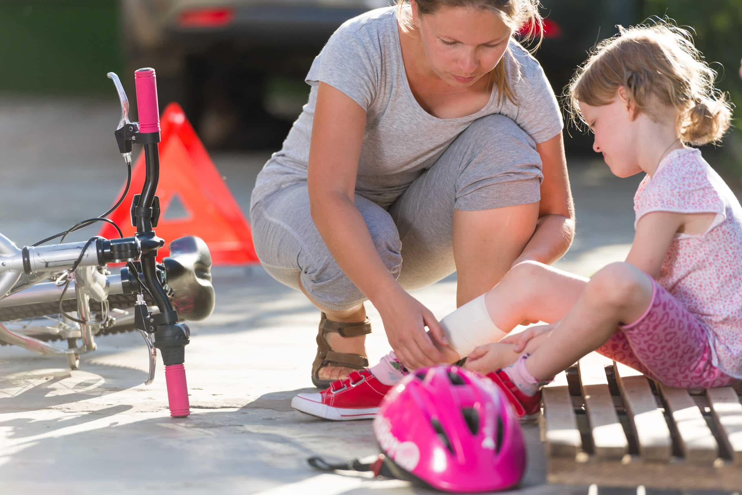 Mom bandaging a young girl's injury