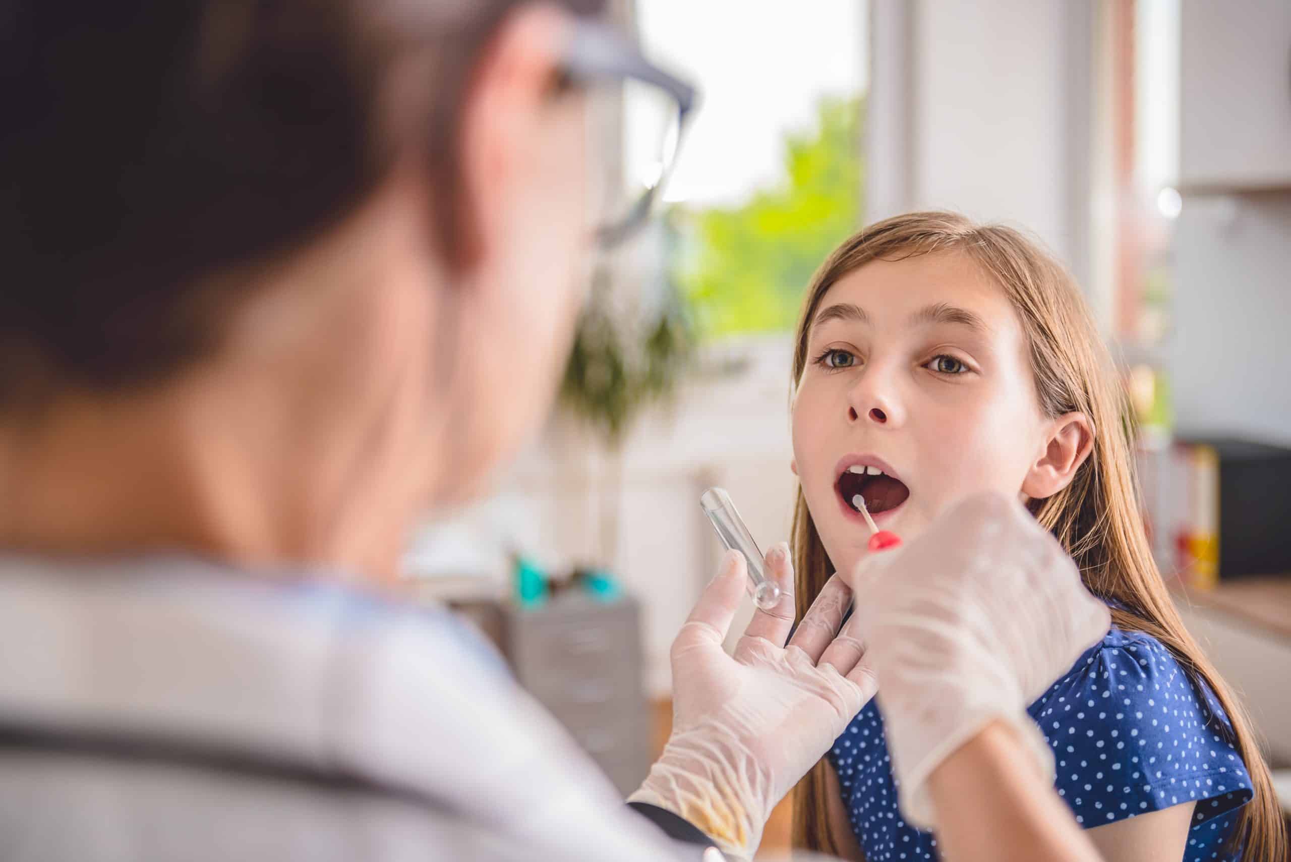 child getting checked for strep throat by a doctor at Urgent Care for Children